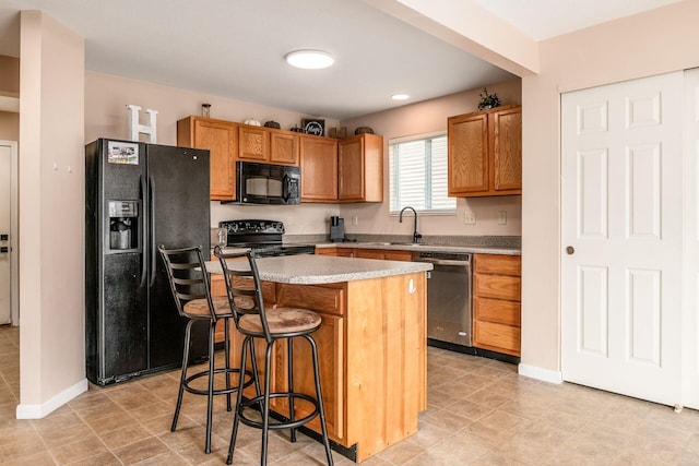 kitchen featuring a kitchen bar, a center island, brown cabinets, a sink, and black appliances