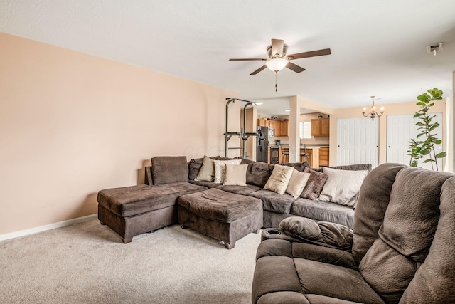carpeted living room featuring baseboards and ceiling fan with notable chandelier