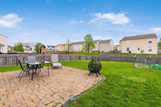 view of patio / terrace featuring a fenced backyard, a playground, a residential view, and an outdoor fire pit