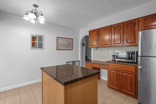 5968 Lisa St, Columbus, OH 43231 - kitchen with appliances with stainless steel finishes, arched walkways, dark countertops, light tile patterned floors, and a textured ceiling