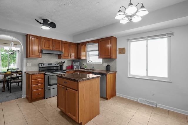 5968 Lisa St, Columbus, OH 43231 - kitchen featuring appliances with stainless steel finishes, a chandelier, under cabinet range hood, a kitchen island, and decorative backsplash