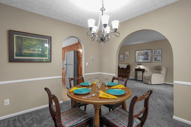 5968 Lisa St, Columbus, OH 43231 - dining space featuring arched walkways, a chandelier, light carpet, a textured ceiling, and baseboards