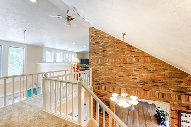 corridor with a textured ceiling, a notable chandelier, an upstairs landing, carpet, and lofted ceiling