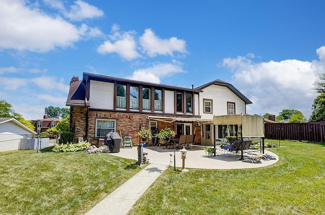 back of property with a patio, a fenced backyard, a lawn, and brick siding