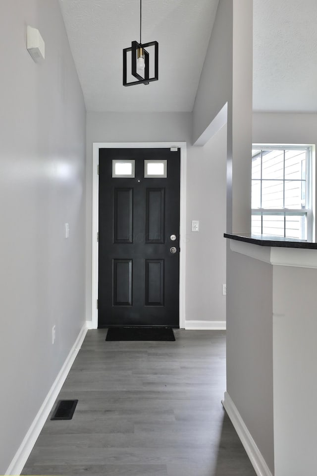 foyer featuring baseboards, wood finished floors, and visible vents