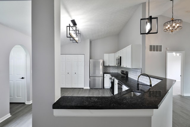 kitchen with visible vents, wood finished floors, high vaulted ceiling, a sink, and appliances with stainless steel finishes