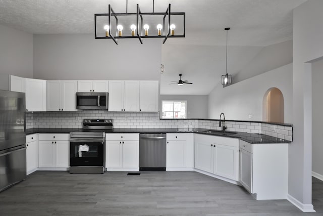 kitchen featuring decorative backsplash, dark countertops, white cabinetry, a sink, and appliances with stainless steel finishes