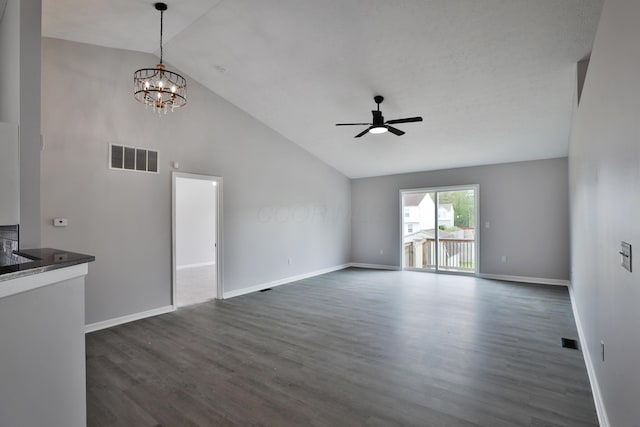 unfurnished living room with dark wood finished floors, ceiling fan with notable chandelier, baseboards, vaulted ceiling, and visible vents