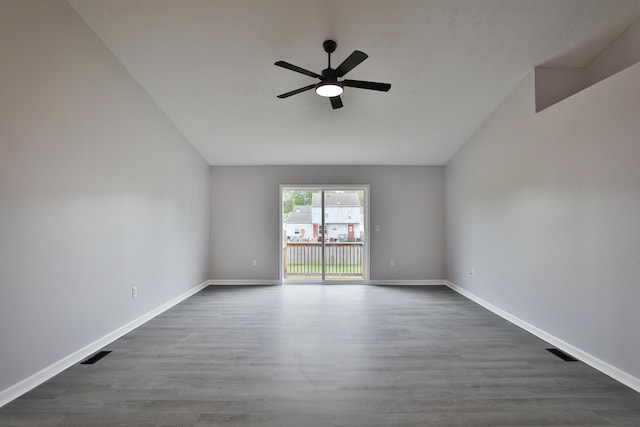 spare room with a ceiling fan, dark wood finished floors, lofted ceiling, and visible vents