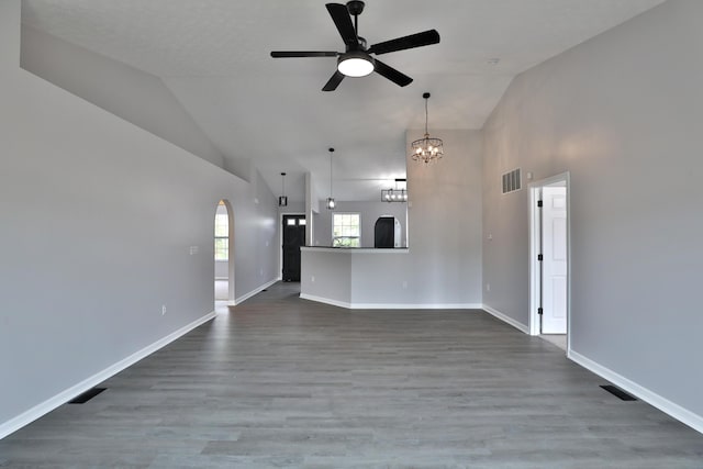 unfurnished living room with high vaulted ceiling, ceiling fan with notable chandelier, and visible vents