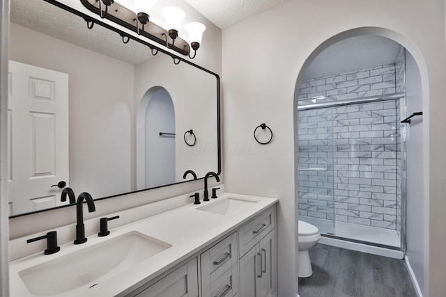 full bathroom featuring a sink, wood finished floors, toilet, and a shower stall