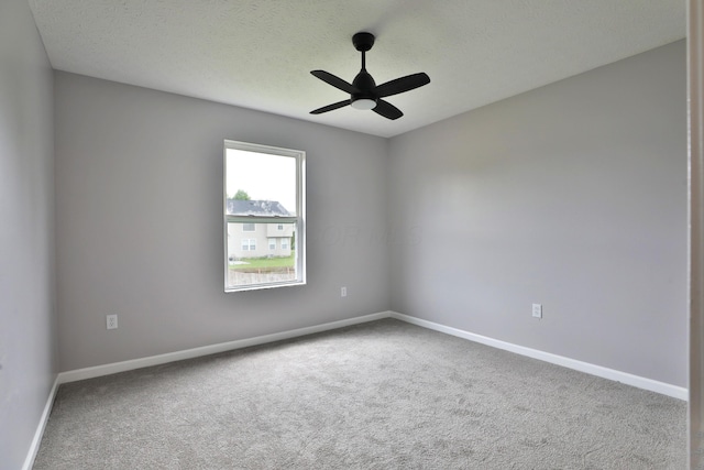 carpeted empty room with a textured ceiling, ceiling fan, and baseboards