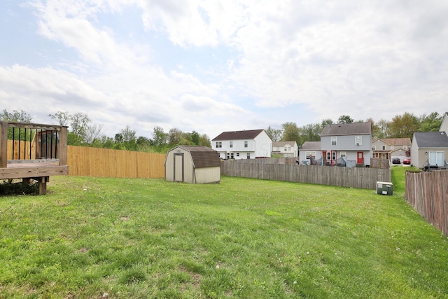 view of yard featuring a fenced backyard, an outbuilding, a storage shed, and a residential view