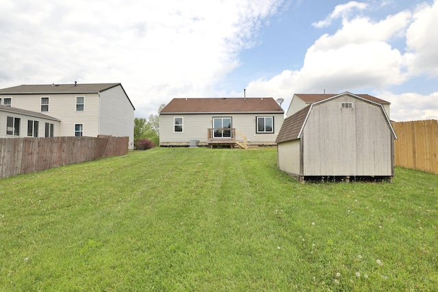 rear view of property with a storage unit, a yard, fence, and an outbuilding