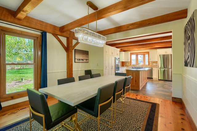 dining space with an inviting chandelier, beamed ceiling, hardwood / wood-style floors, and visible vents