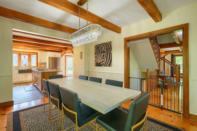 dining space featuring beamed ceiling, hardwood / wood-style flooring, and a notable chandelier