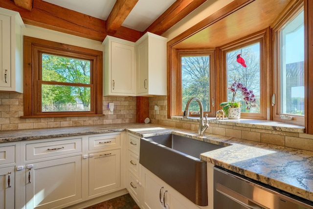kitchen with white cabinets, a sink, tasteful backsplash, stainless steel dishwasher, and beamed ceiling