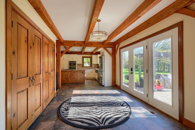 entryway featuring stone tile floors, baseboards, visible vents, and beam ceiling
