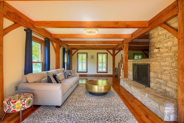 living room with plenty of natural light, beam ceiling, hardwood / wood-style flooring, and a fireplace