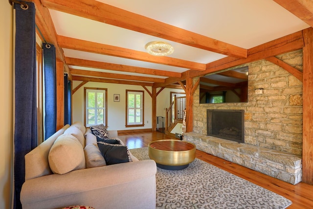 living area with a fireplace, beamed ceiling, stairs, and wood finished floors