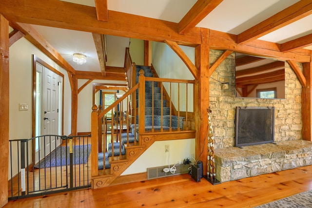 unfurnished living room featuring visible vents, a stone fireplace, beam ceiling, and hardwood / wood-style floors