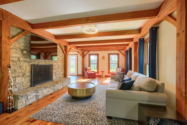 living area with wood finished floors, a fireplace, and beamed ceiling