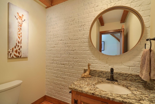 bathroom featuring vanity, baseboards, wood finished floors, and toilet