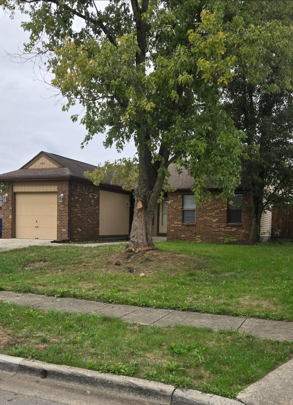 ranch-style house featuring brick siding, a garage, a front lawn, and concrete driveway