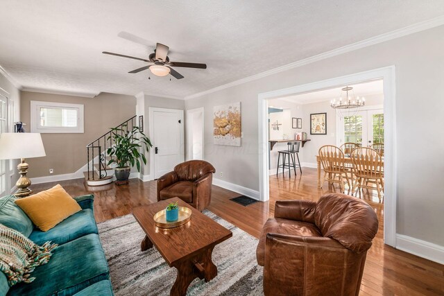 living room featuring baseboards, stairs, ceiling fan with notable chandelier, and wood finished floors