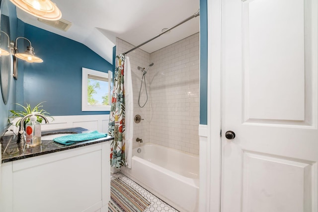 bathroom with tile patterned flooring, vanity, shower / bathtub combination with curtain, vaulted ceiling, and visible vents