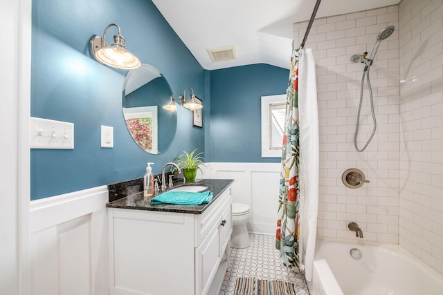 full bath featuring vanity, toilet, shower / bath combination with curtain, a wainscoted wall, and visible vents