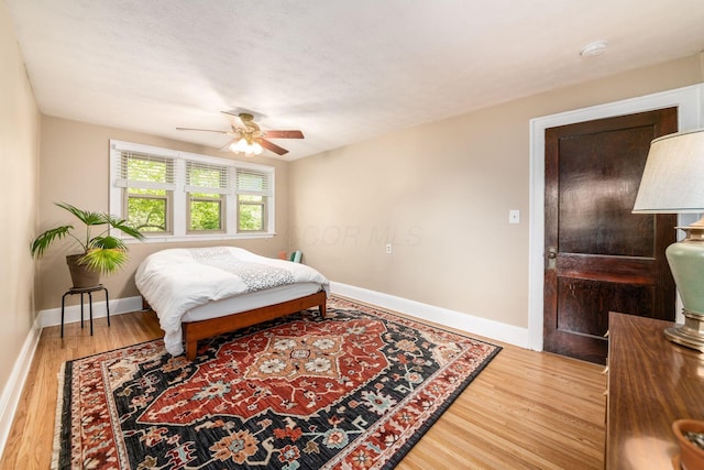 bedroom featuring baseboards, ceiling fan, and wood finished floors