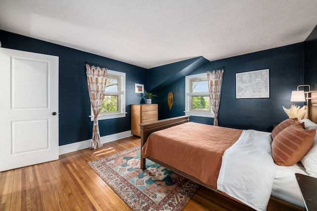 bedroom with baseboards, multiple windows, and wood finished floors
