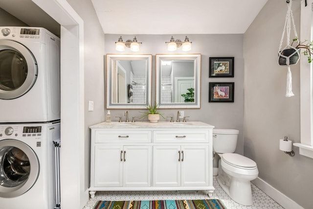 bathroom featuring a sink, baseboards, stacked washer and clothes dryer, and toilet