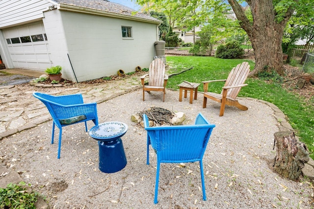 view of patio / terrace featuring a garage, a fire pit, and fence