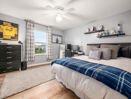 bedroom with baseboards, ceiling fan, and wood finished floors