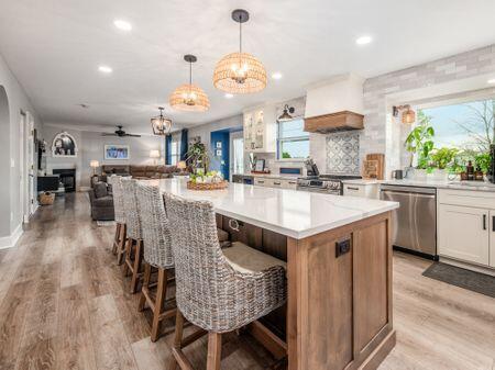 kitchen with dishwasher, stove, a large island, light wood-type flooring, and custom exhaust hood