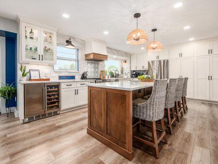 kitchen with freestanding refrigerator, recessed lighting, a center island, white cabinets, and custom range hood