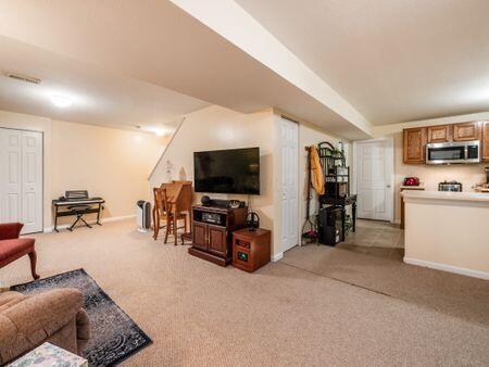living area featuring baseboards and light carpet