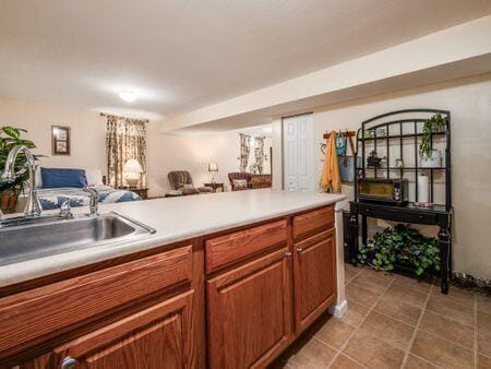 kitchen featuring brown cabinets, light tile patterned floors, light countertops, a sink, and open floor plan