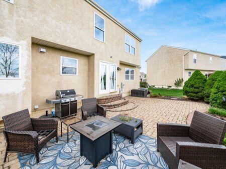 back of property featuring a patio, an outdoor living space with a fire pit, stucco siding, and entry steps