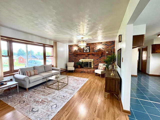 living room with baseboards, a fireplace, brick wall, and wood finished floors
