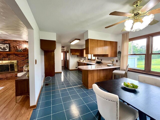 kitchen featuring light countertops, a peninsula, baseboards, and brown cabinetry