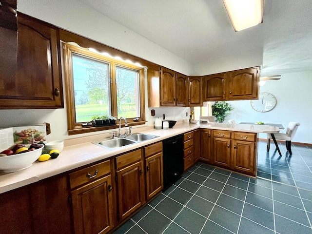 kitchen with black dishwasher, dark tile patterned floors, a sink, and light countertops
