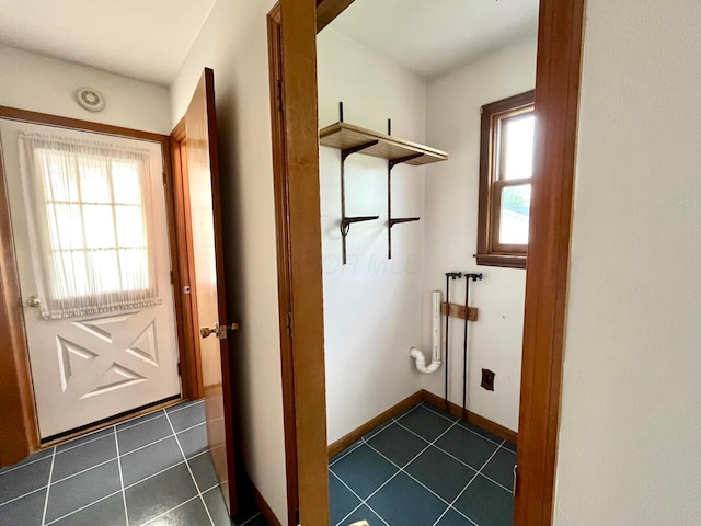 doorway to outside with dark tile patterned floors and baseboards