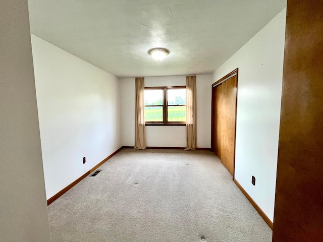 interior space featuring baseboards, light carpet, and visible vents