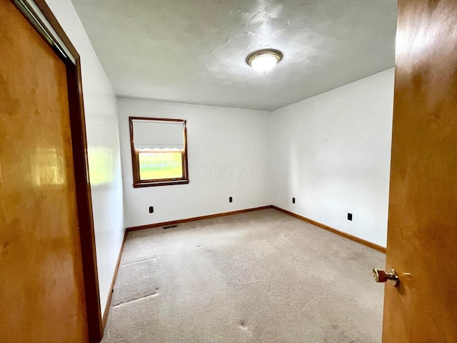 unfurnished room featuring carpet floors, baseboards, and visible vents