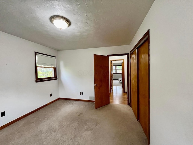 carpeted empty room with baseboards, visible vents, and plenty of natural light