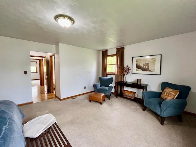 sitting room with baseboards, visible vents, and carpet