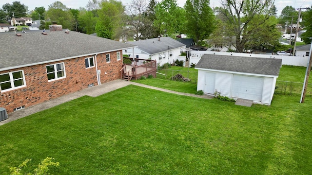 view of yard with fence, an outdoor structure, a garage, and a wooden deck
